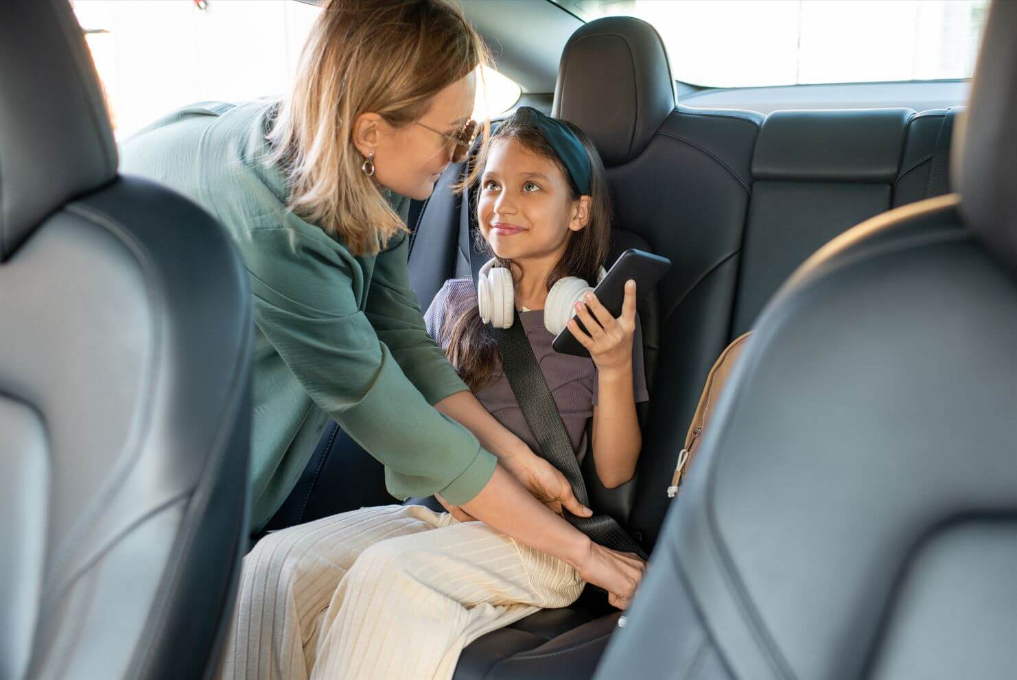 A woman fastens a child's seat belt.